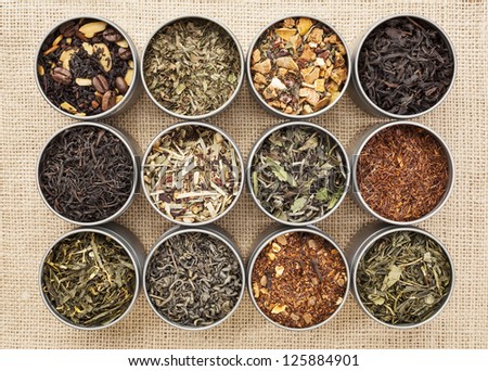 samples of loose leaf green, white, black and herbal tea in metal cans on canvas background