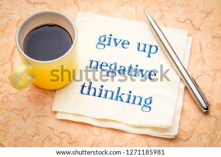 give up negative thinking - inspirational handwriting on napkin with a cup of color