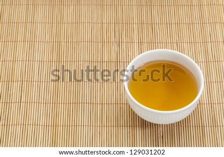 white china cup of green tea against bamboo place mat