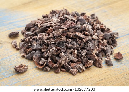 Close-up of a pile of raw cacao nibs on a grunge wooden background