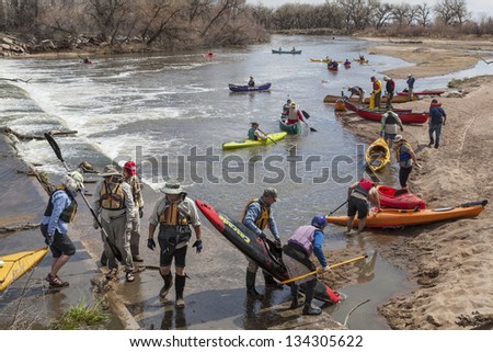 SOUTH PLATTE RIVER, EVANS, COLORADO - APRIL 6: Portaging kayak and canoes over a river diversion dam during Annual All Club Paddle on April 6, 2013. It is a popular season opening paddling trip.