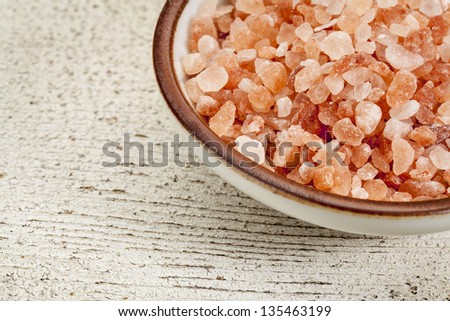 Himalayan salt coarse crystals in a ceramic bowl on  a rough white painted barn wood