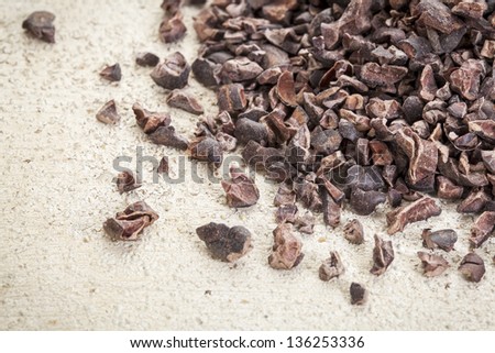 Close-up of a pile of raw cacao nibs on a rough white painted barn wood background