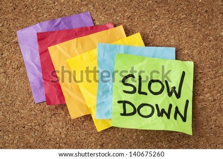 slow down - lifestyle concept or advice - handwriting on colorful sticky notes