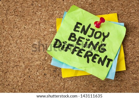 enjoy being different advice - lifestyle or nonconformist concept - handwriting on green sticky note