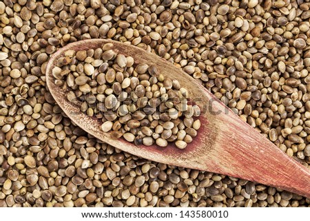 background of organic dried hemp seeds with a rustic wooden spoon