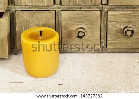 bee wax candle in retro setting with a primitive apothecary drawer cabinet