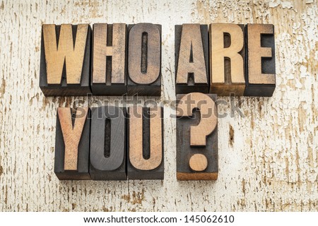 who are you question in vintage letterpress wood type on a grunge painted barn wood background