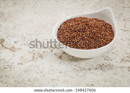 small ceramic bowl of  red quinoa grain against a ceramic tile background with a copy space