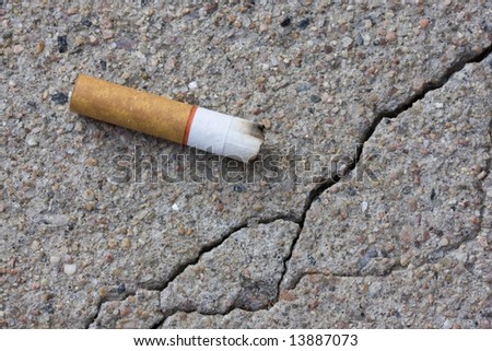 macro shot of a cigarette butt thrown on a concrete cracked sidewalk
