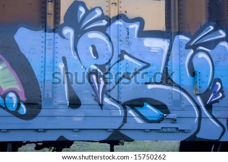 blue graffiti on a rusty freight train car