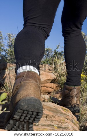 hiker legs with heavy leather shoes and black tights on a mountain uphill trail