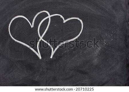 two interlaced hearts sketched with white chalk on a blackboard