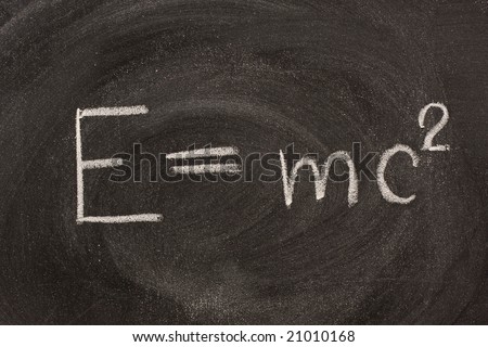 Albert Einstein well known physical formula, E=mc2, describing equivalence of matter mass (m) and energy (E) with including speed of light.  It is handwritten with white chalk on school blackboard