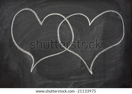 two blank speech bubbles (callouts) in the form of interlaced hearts sketched with white chalk on blackboard