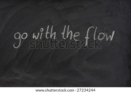 go with the flow phrase handwritten with white chalk on blackboard with erase smudge patterns