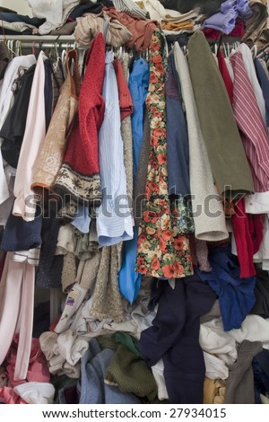 messy closet overfilled with colorful woman clothes on hangers and stuffed in any available space