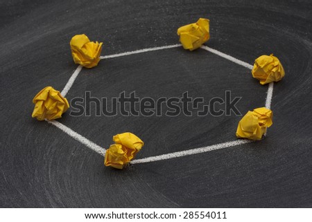 model of ring network with a single direction data flow made with yellow crumbled paper nodes, white chalk connection lines and blackboard with eraser smudges in background