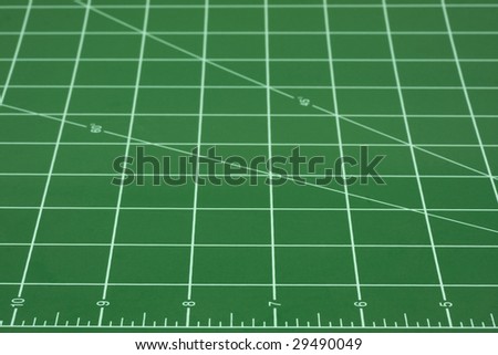green self healing cutting mat with grid of white converging lines, focus on inch ruler in front
