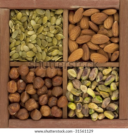 four healthy raw snacks, almonds, hazelnuts, pistachio nuts and pumpkin seed, in a rustic wooden box or drawer with dividers