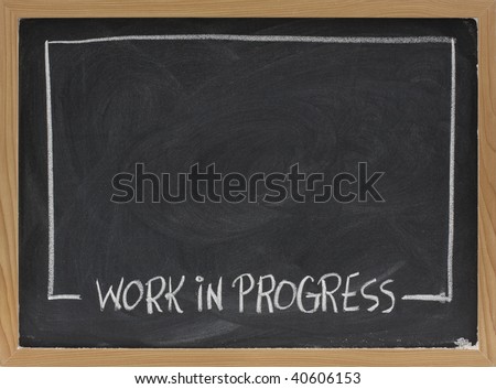 work in progress text in white chalk handwriting, rectangular frame on blackboard with eraser smudge patterns and blank copy space