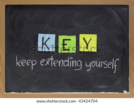 KEY (keep extending yourself) - coaching, motivational, self development acronym, white chalk handwriting and colorful sticky notes on blackboard