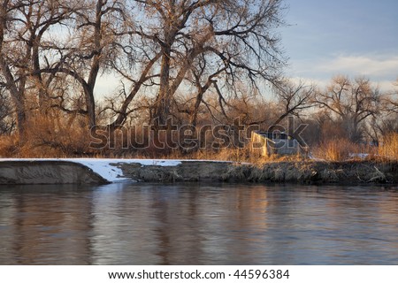 old blind for waterfowl hunting on shore of South Platte River, Colorado near Greeley, winter scenery with cottonwoods and some snow
