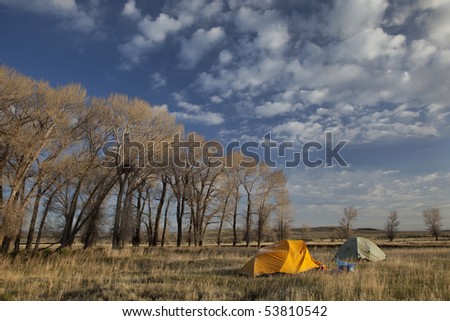 two tents cover by frost in early morning next to stand of cottonwood with eagle nest, North Platte River valley in Wyoming