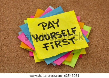 pay yourself first, a reminder of personal finance strategy - stack of colorful sticky notes on a cork bulletin board