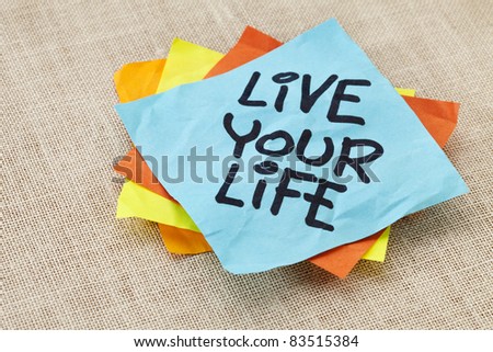 live your life - spiritual reminder - handwriting on a blue sticky note against canvas