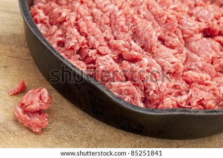 raw ground bison (buffalo)  meat on an iron pan against wood surface