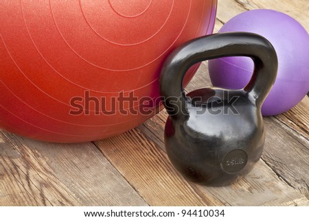 black iron kettlebell, Swiss and medicine exercise balls on wooden deck - fitness concept