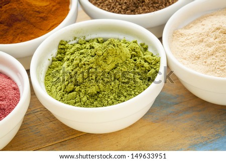 moringa leaf powder in a small bowl among other super fruit powders