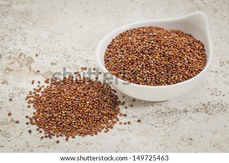 small ceramic bowl of  red quinoa grain against a ceramic tile background