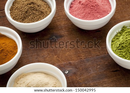 super fruit and leaf powders in small ceramic bowls with copy space - baobab, nori, yumberry, moringa, mangosteen