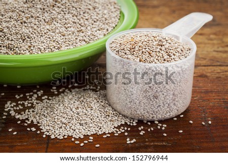 white chia seeds -measuring scoop and small side dish bowl against grunge wooden surface