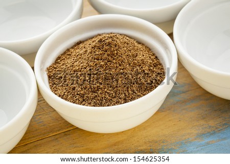 raw organic dried noni (Morinda citrifolia,)  fruit powder in a small ceramic bowl