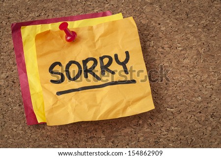 sorry apology - black ink handwriting on an orange sticky note