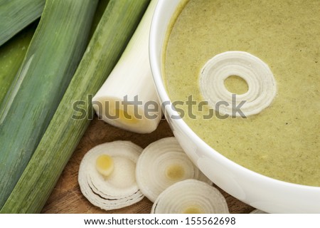 a bowl of leek cream soup with green fresh leeks
