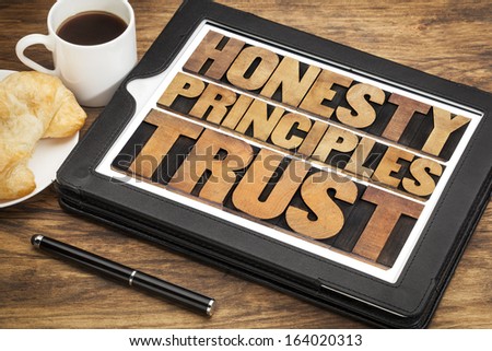 honesty, principles and trust words in vintage letterpress wood type on a touchscreen of digital tablet with a cup of coffee