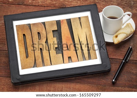 dream word in wood type on a digital tablet with a cup of coffee