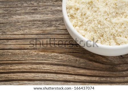 almond flour high in protein, low in carbohydrates, low in sugars and gluten free - a ceramic bowl on grained wood background