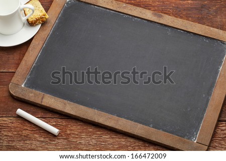 blank vintage slate blackboard with a chalk on wood table with a cup of coffee