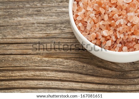 Himalayan salt coarse crystals in a ceramic bowl on  a grained wood