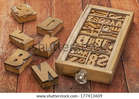 letterpress wood type blocks in a typesetter drawer against rustic red barn wood