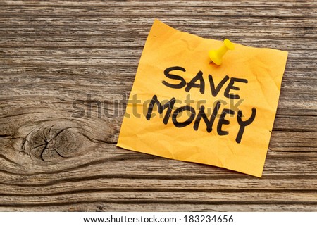 save money yellow reminder note against grained wood