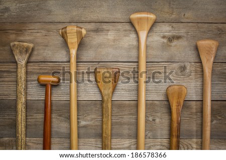 grips and shafts of old wooden canoe paddles against weathered wood background
