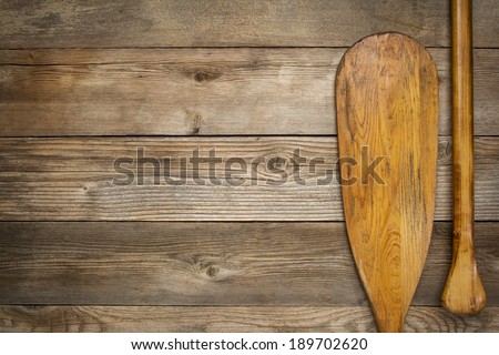 blade and grip of wooden canoe paddle against a wood background with a copy space