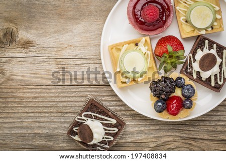 dessert - tarts with strawberry on white plate against grained weathered wood