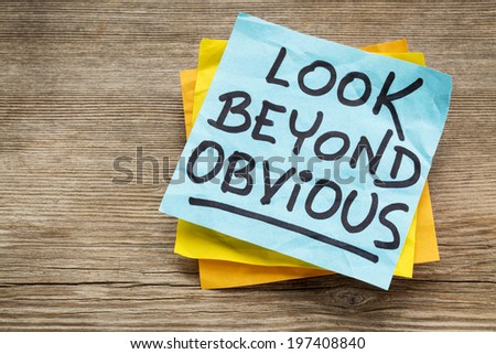 look beyond obvious - creativity and motivation reminder on a sticky note against grained wood